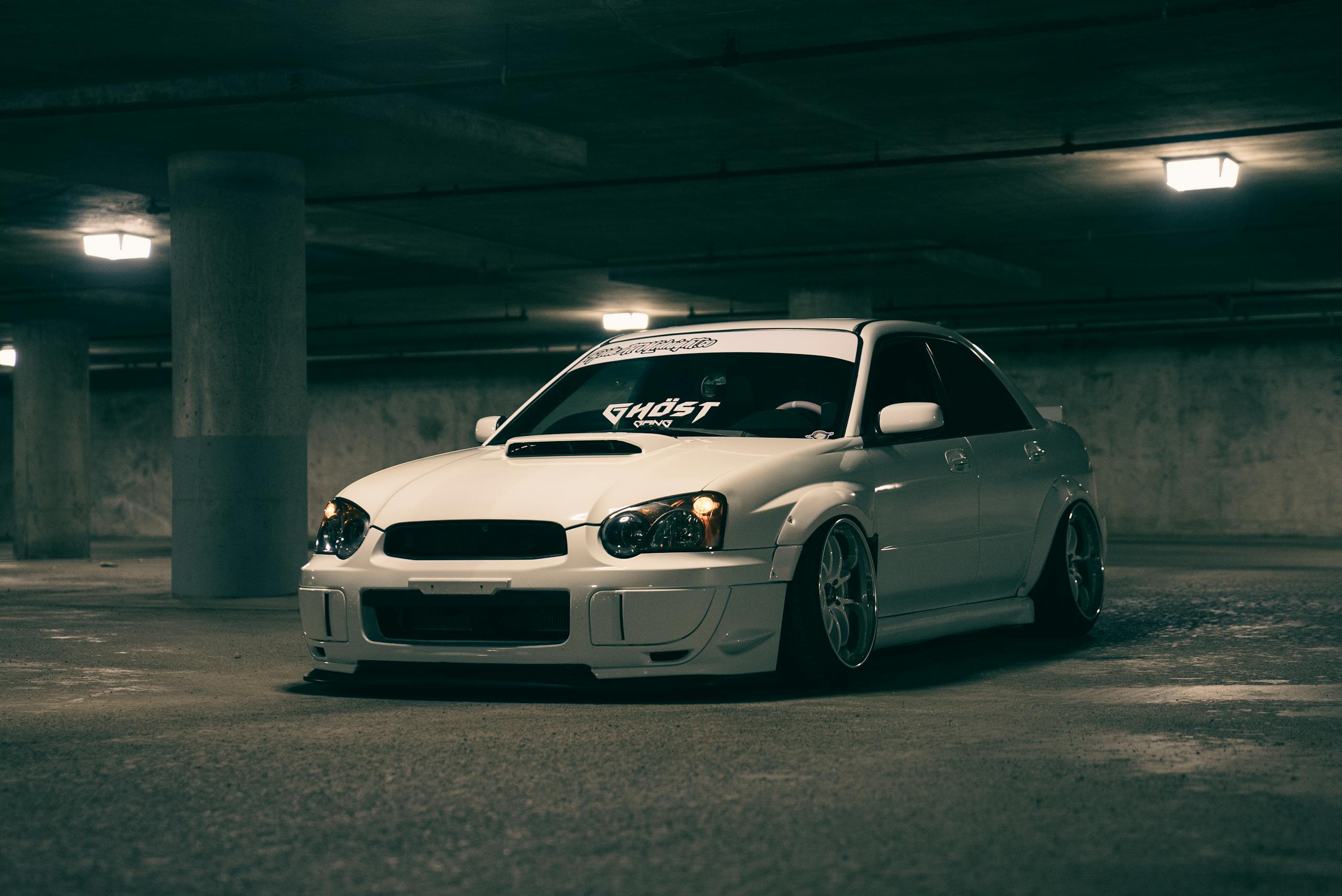 Eerily lit white sports car parked in an empty urban garage evoking a sense of adventure.